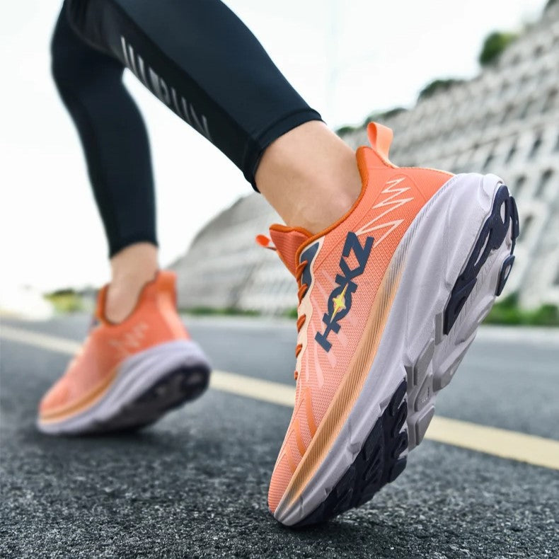 Scarpe da corsa arancioni su strada asfaltata, indossate da persona in leggings neri. Scarpe sportive leggere, ideali per jogging e fitness all'aperto.