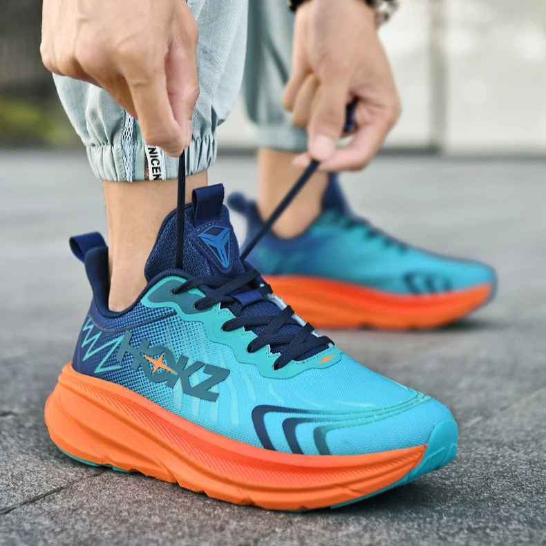 Scarpe da corsa blu e arancioni su pavimento grigio, con design moderno e suola ammortizzata. Uomo allaccia i lacci. Scarpe sportive comode.
