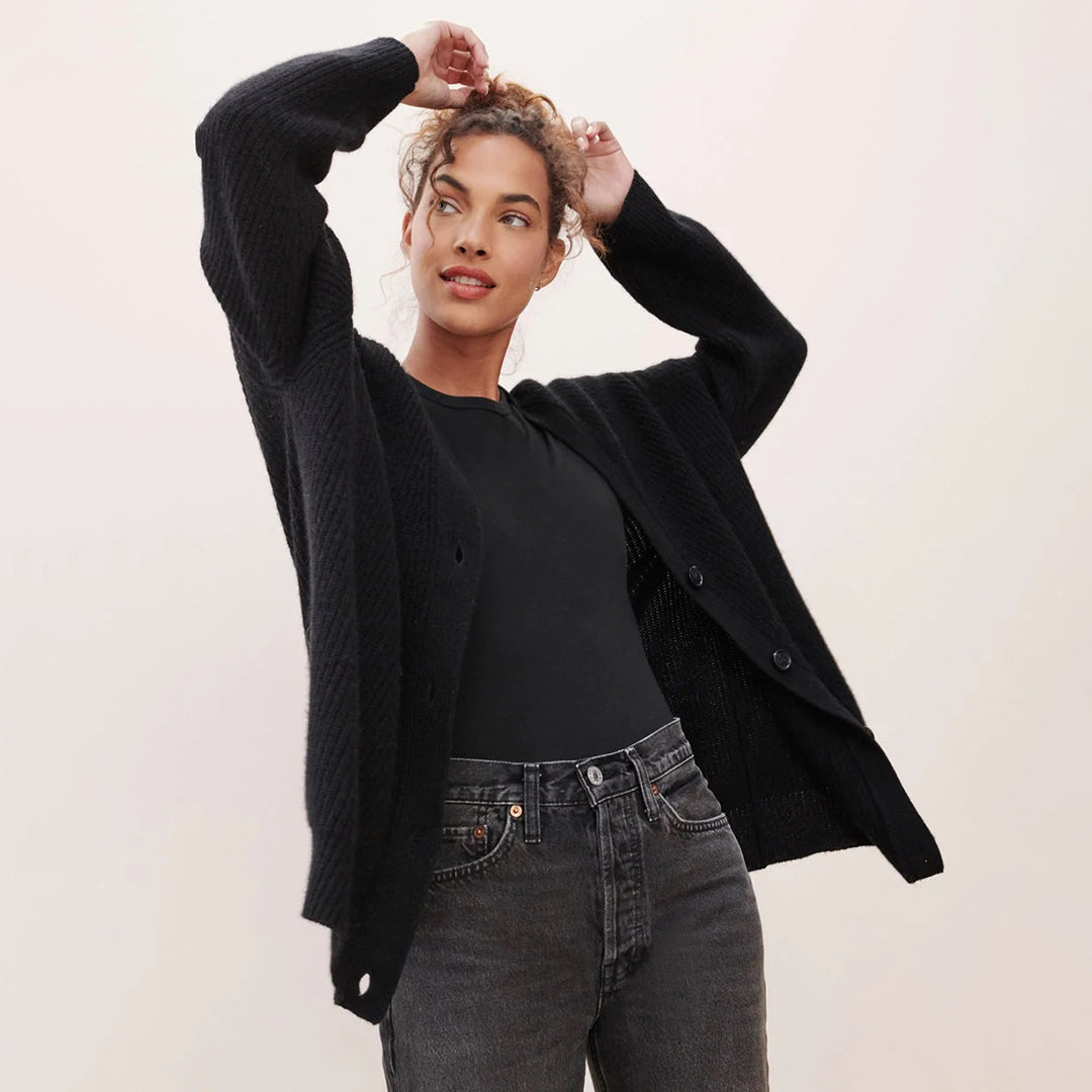 Donna con cardigan nero, maglietta nera e jeans grigi. Moda autunnale, abbigliamento casual elegante, stile contemporaneo.