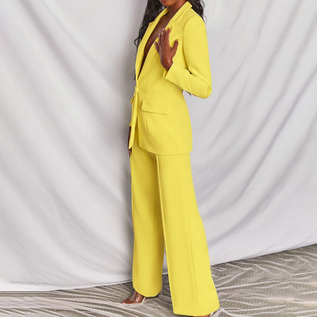 Completo donna elegante giallo, giacca e pantaloni larghi, moda contemporanea, abbigliamento formale, tessuto liscio, sfondo bianco.