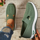 Scarpe da donna verdi in maglia traspirante, suola bianca, indossate con jeans strappati e cavigliera. Stile casual e comodo per passeggiate.