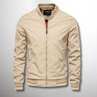 Giacca bomber beige da uomo, chiusura zip, colletto rialzato, polsini e orlo elasticizzati. Stile casual, moda maschile, abbigliamento autunnale.