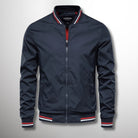 Giacca bomber blu scuro con zip, colletto e polsini a righe rosse e bianche. Moda uomo, abbigliamento casual, stile sportivo.