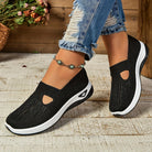 Scarpe da ginnastica nere da donna, design traspirante, suola bianca, indossate con jeans strappati. Stile casual, moda estiva, comfort quotidiano.