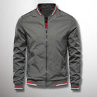 Giacca bomber grigia da uomo con zip, colletto e polsini a righe rosse e bianche. Moda casual, abbigliamento autunnale, stile urbano.