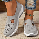 Scarpe da donna grigie in maglia traspirante, suola bianca, indossate con jeans strappati e cavigliera con pietre turchesi. Moda casual estiva.