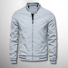 Giacca bomber grigia da uomo, stile casual, con zip frontale e polsini a righe. Perfetta per moda autunnale e look urbano.