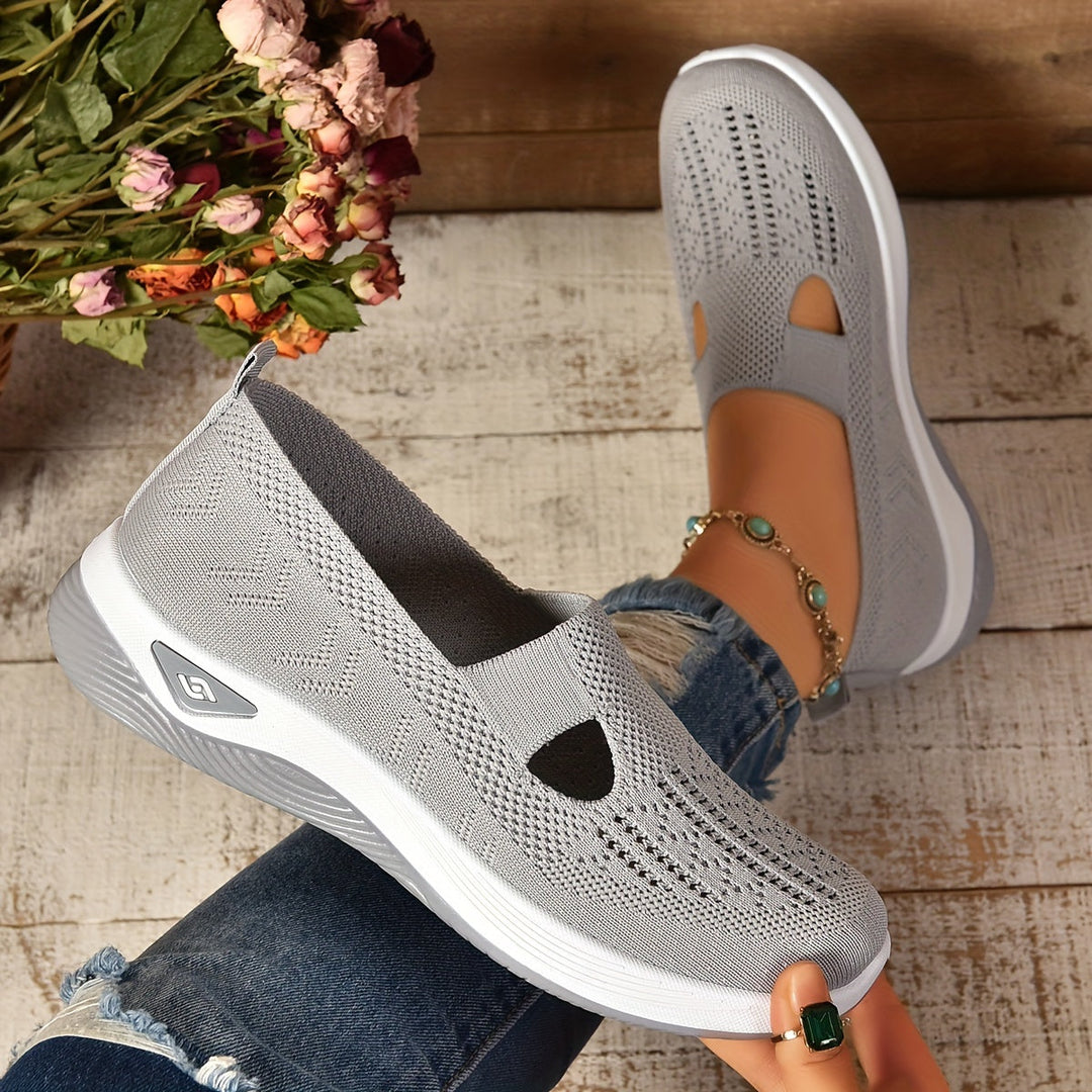 Scarpe da donna grigie in maglia traspirante, suola bianca, indossate con jeans strappati. Design casual e comodo, perfetto per passeggiate estive.