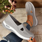 Scarpe da donna grigie in maglia traspirante, suola bianca, indossate con jeans strappati. Design casual e comodo, perfetto per passeggiate estive.