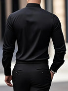 Uomo in camicia nera elegante, visto di spalle, cammina in ambiente urbano. Moda maschile, abbigliamento formale, stile contemporaneo.