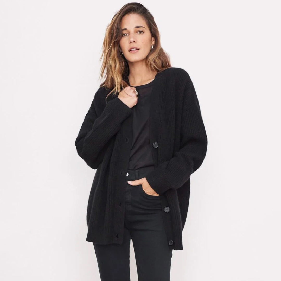 Donna con cardigan nero, maglietta e pantaloni scuri. Moda autunnale, abbigliamento casual elegante, stile minimalista. Sfondo bianco.