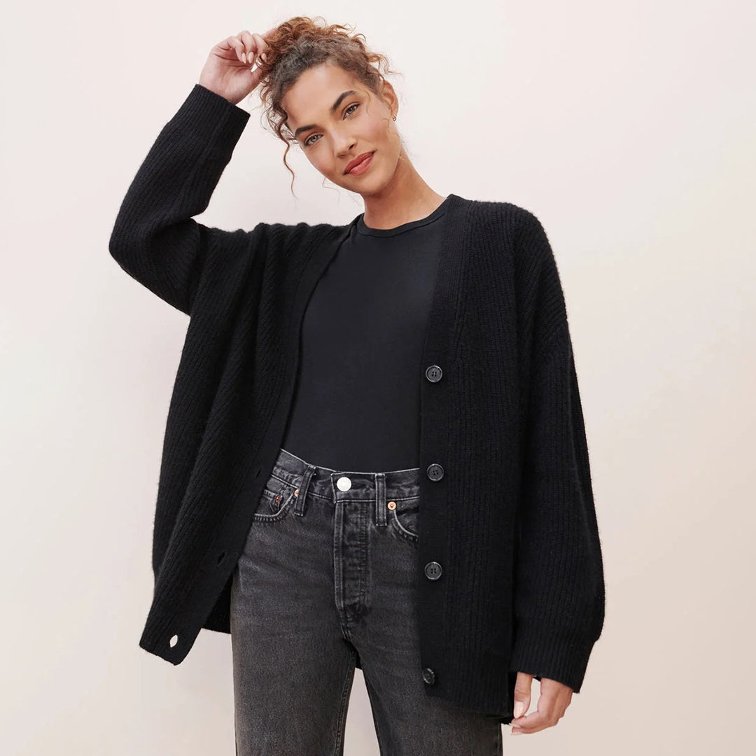 Donna con cardigan nero oversize, maglietta nera e jeans grigi. Moda casual autunnale, abbigliamento femminile elegante e confortevole.