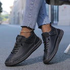 Scarpe sportive nere in pelle, indossate con jeans chiari. Design casual, suola robusta, perfette per passeggiate urbane. Moda streetwear.