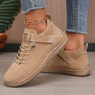 Scarpe sportive beige da donna, design casual con suola in gomma antiscivolo, lacci e cinturino, abbinate a jeans aderenti e cavigliera dorata.