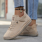 Scarpe sportive beige da donna in pelle scamosciata, abbinate a jeans aderenti. Design casual, suola antiscivolo, perfette per passeggiate urbane.
