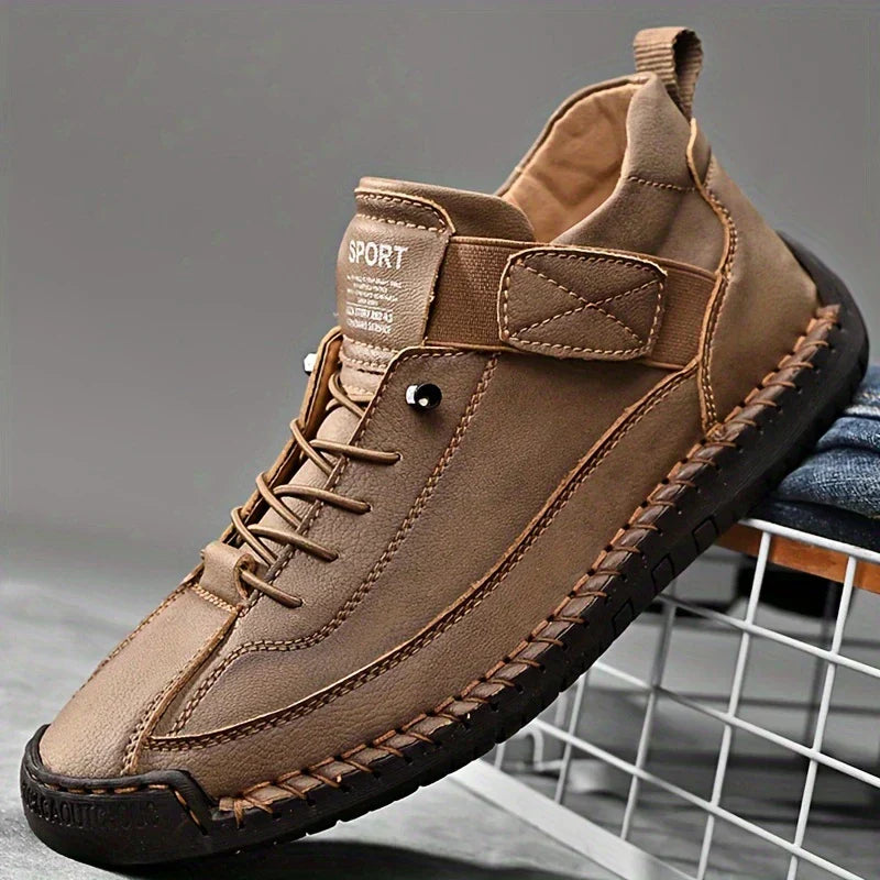 Scarpa sportiva casual marrone da uomo con suola in gomma nera, design moderno e lacci, posizionata su una griglia metallica.