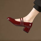 Scarpa Mary Jane rossa lucida con tacco largo, doppio cinturino e fibbie argentate, indossata su sfondo marrone. Scarpe eleganti donna.
