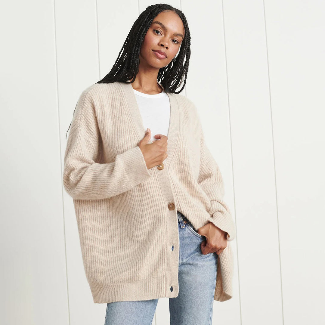 Donna con cardigan beige oversize, maglietta bianca e jeans chiari. Moda casual autunnale, stile confortevole ed elegante. Sfondo bianco minimalista.
