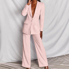 Donna in elegante completo pantalone rosa, giacca lunga, sfondo bianco. Moda femminile, abbigliamento formale, tendenze 2023.