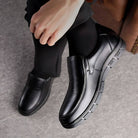 Scarpe eleganti da uomo in pelle nera, design slip-on, suola antiscivolo, indossate con pantaloni scuri. Ideali per look formale e business.