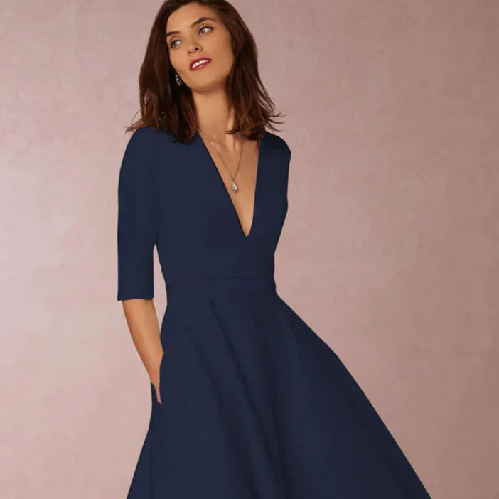 Abito elegante blu scuro con scollo a V e maniche a tre quarti, indossato da una donna su sfondo neutro. Moda femminile, abbigliamento chic.