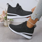 Scarpe da ginnastica nere con zeppa, design traforato, indossate con jeans chiari. Sfondo con fiori decorativi. Moda casual donna.