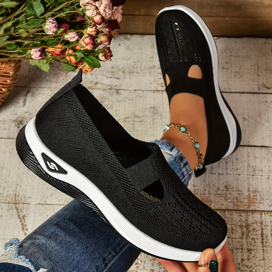 Scarpe da donna nere in tessuto traspirante, suola bianca, indossate con jeans. Design casual e moderno, perfette per passeggiate e tempo libero.