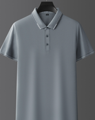 Polo grigia elegante su sfondo grigio, con colletto e bottoni, perfetta per look casual e formali. Maglietta uomo moda 2023.