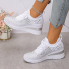 Scarpe da ginnastica bianche da donna con zeppa, dettagli in pizzo, indossate con jeans strappati. Scarpe moda casual eleganti e comode.