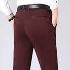 Pantaloni eleganti uomo marroni, tasche posteriori, cintura nera, camicia bianca. Moda maschile, abbigliamento formale, stile classico.
